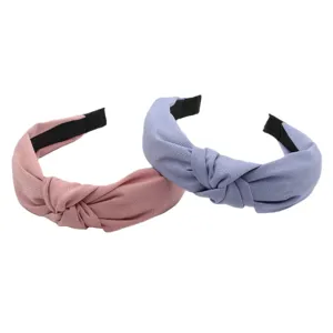 Detailed closeup of cross knotted fabric headbands in solid pink and blue-grey colors.