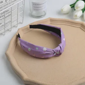 Detail view of a purple floral knotted headband, aesthetic desktop display with minimalist props for daily wear.