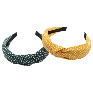 Closeup view of stylish fabric polka dot knotted headbands in bright green and yellow.