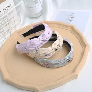 Close-up detail of stylish floral knotted headbands in pink, yellow, and grey colors.