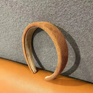 Close-up detail shot of a stylish brown padded headband with textured fabric surface.