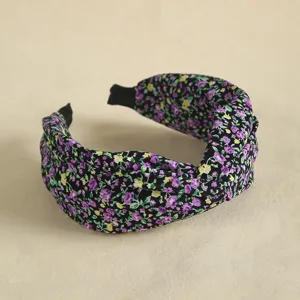 Close-up detail of the black floral fabric headband, showing the twisted knot texture.