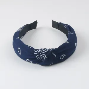 Vue en gros plan détaillée du serre-tête en tissu paisley bleu foncé avec un nœud.