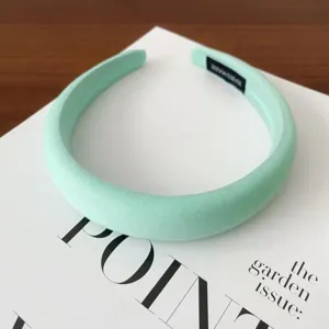 Mint green wide padded headband with soft fabric cover, chic daily hair accessory detail shot.