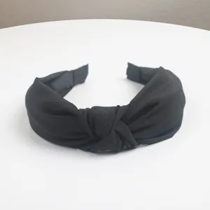 Detail shot of black twill knotted headband, showing texture and central knot design close up.