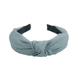 Gros plan détaillé sur l'élégant accessoire de serre-tête en tissu gris-bleu noué.