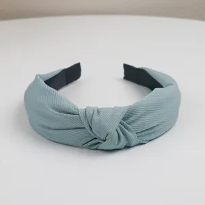 Detail view of the solid color textured fabric knotted headband, stylish wide hair accessory.