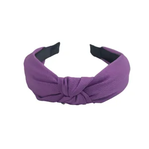 Gros-plan sur le serre-tête noué en tissu violet, texture côtelée et design large élégant.