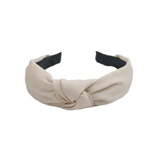 Gros plan du serre-tête en tissu beige noué, design large, texture douce pour accessoire quotidien.