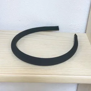 Detailed view of a simple black padded sponge headband placed on a wooden shelf.