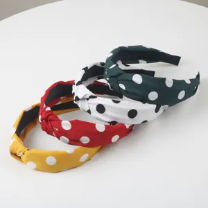 Gros plan détaillé de bandeaux larges noués en tissu à pois multicolores pour femmes.