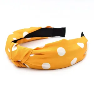 Vue rapprochée détaillée du bandeau en tissu jaune élégant avec pois blancs et nœud chic.