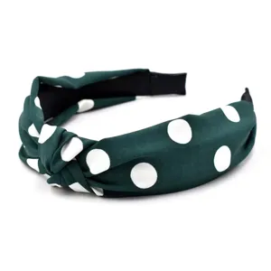 Vue détaillée de l'élégant bandeau en tissu vert foncé à pois avec un beau nœud.