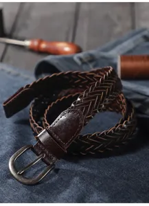 Close-up details of dark brown woven leather belt featuring a classic metal pin buckle.