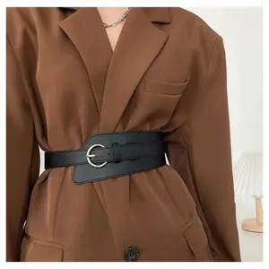 Close-up detail of women's wide black fashion waist belt corset style worn with brown blazer.