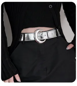 Silver glossy leather belt with metal moon buckle, stylish accessory for women's outfits.