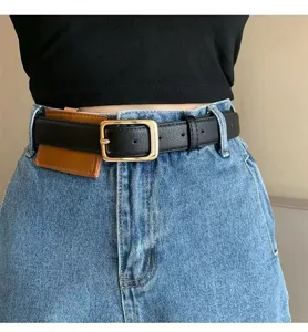 Close-up detail view of black leather belt featuring gold buckle and mini pouch on denim.