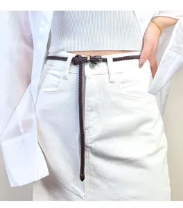 Nahaufnahme eines schmalen dunkelbraunen geflochtenen Ledergürtels zu weißem Outfit.