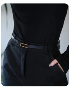 Detailed shot of a sleek black thin leather belt featuring a modern gold U-shaped buckle.