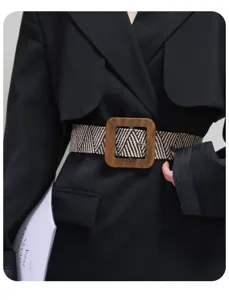 Close-up of a wide woven elastic belt featuring a vintage square wooden buckle for women.