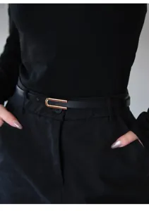Close-up detail shot of black slim leather belt featuring chic gold U-shaped buckle.