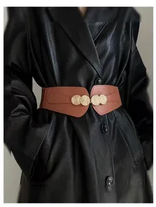 Detailed view of women wide brown elastic waist belt with gold coin buckle accent.