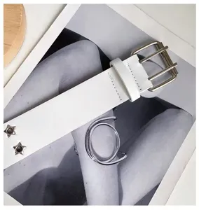 Detail shot of white punk leather belt featuring star rivets and metallic spiral accessory.