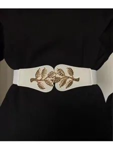 Gros plan sur la ceinture élastique blanche dotée d'un fermoir en métal doré en forme de feuille.