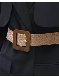 Woven wide belt detail featuring a large square wooden buckle styled over a black blazer jacket.