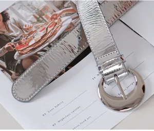Silver metallic glossy leather belt detail, stylish large metal buckle, fashion accessory.