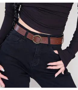 Detailed view of the retro brown leather belt with a vintage round metal buckle worn.