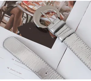 Silver glossy leather belt for women, stylish metal buckle, perfect accessory for dresses and jeans.