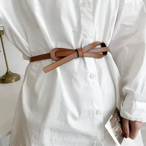 Stylish brown thin leather belt for women, retro bow waist accessory for dress shirts.