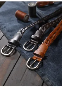 Detailed view of handmade woven leather belts in brown and black with metal buckles.