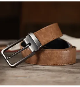 Close up detail view of a vintage brown leather belt with metal pin buckle for jeans.