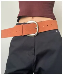 Retro suede belt detail showing stylish brown texture and chunky silver metal buckle.