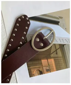 Gros plan détaillé de la ceinture en cuir marron foncé avec des rivets argentés et boucle.