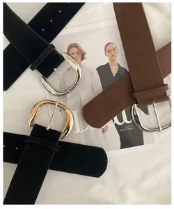 Close-up detail of retro suede belt featuring smooth metallic buckle and texture.