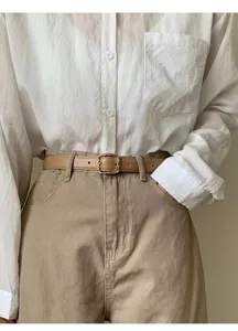 Close-up of a stylish thin leather belt with an elegant metallic square buckle for outfits.