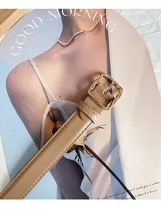 Close-up detail of women's beige belt with a chic twisted gold square buckle, elegant design.