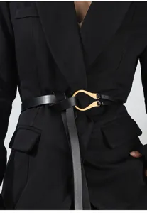 Close-up of black leather belt with gold metal U-buckle worn on a chic black blazer jacket.