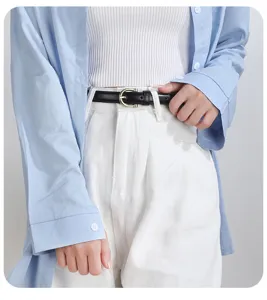 Cintura da donna sottile in pelle nera minimalista con fibbia dorata su pantaloni bianchi