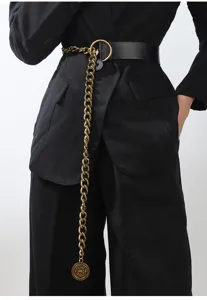 Close-up of stylish black leather belt with golden chain and medallion for women outfits.