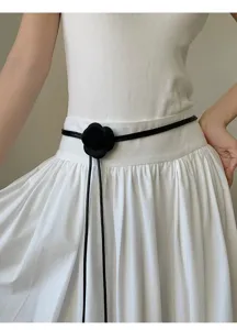 Primer plano detallado del elegante cinturón de cintura con flor de camelia negra y textura.