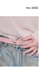 Close-up detail of the pink leather belt with sparkling rhinestone star buckle worn on denim.