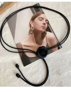 Detalle de cinturón de flor de camelia negra, cuerda de cuero fino vintage para vestidos de mujer.