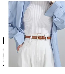 Primo piano dettaglio di una sottile cintura in pelle marrone minimalista su pantaloni bianchi.