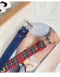 Close-up detail of Y2K style denim and red plaid canvas belts with metal buckle and flower.