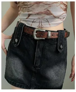 Close up view of the retro ethnic style brown embossed leather belt with ornate silver metal buckle.
