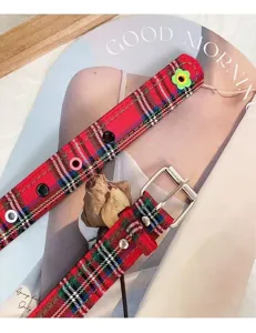 Detail shot of a Y2K red plaid canvas belt with metal eyelets and flower decor, style.